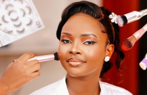 How To Apply The Perfect MakeUp A beautiful Black woman with flawless makeup sits confidently as a makeup artist applies final touches, showing how to apply the perfect makeup with precision and care.