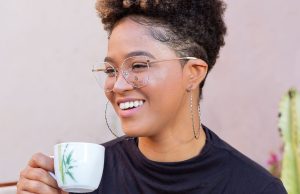 How To Live A Soft Life A relaxed woman smiling softly while holding a coffee cup, capturing the calm and peaceful feeling of how to live a soft life.