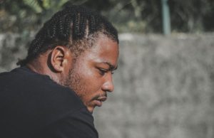 How To Be Mentally Strong A black man with cornrows looking calm and reflective outdoors, representing how to be mentally strong and maintain resilience during life’s challenges.