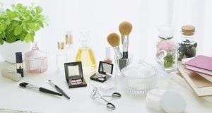 The Best Makeup Tips For Beginners Minimalist flat lay with makeup brushes, eyeshadow palette, mirror, cotton pads, notebook, and a plant on a white table — illustrating the best makeup tips for beginners.