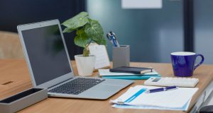 How To Start a Business with No Money A minimal workspace with a laptop, notebook, coffee cup, calculator, and small plant — representing how to start a business with no money from home.