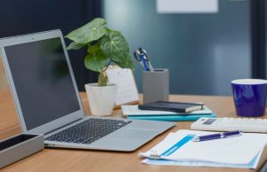 How To Start a Business with No Money A minimal workspace with a laptop, notebook, coffee cup, calculator, and small plant — representing how to start a business with no money from home.