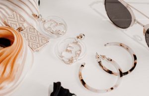 The Top 10 Fashion Trends For 2023 Neutral fashion accessories including jewelry and sunglasses on a white table, representing the top fashion trends for 2023 in minimalist and sustainable style.