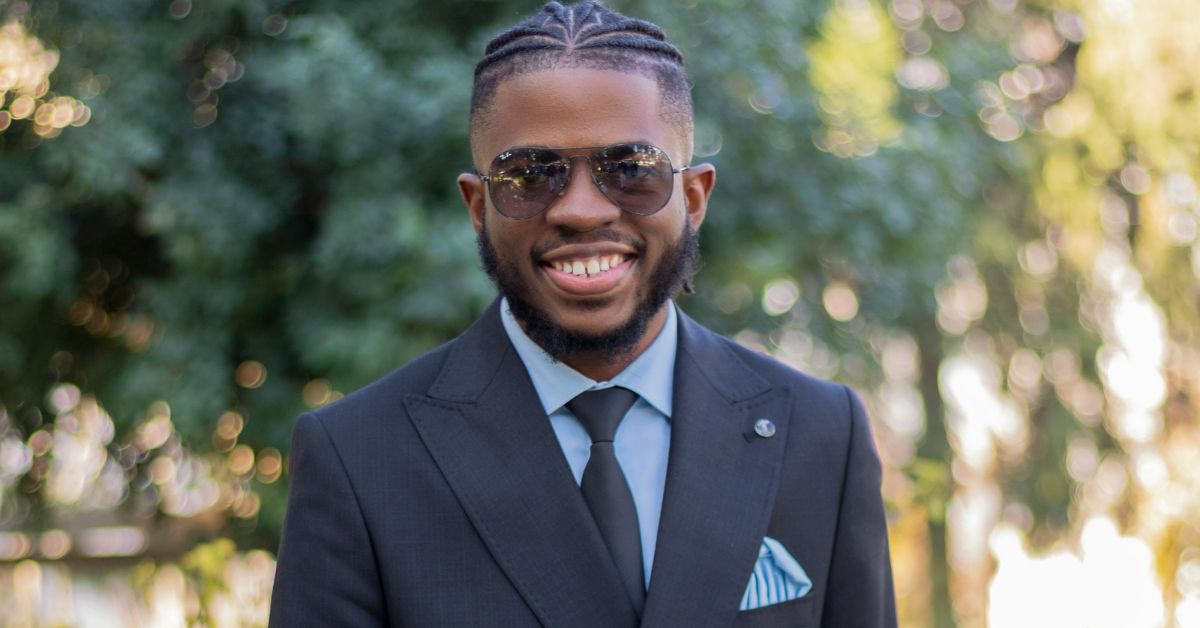 Confident black man in suit smiling outdoors, representing how to build self-confidence through style and positive mindset