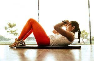 The Top 10 Health Benefits Of Exercise A woman exercising on a yoga mat indoors, demonstrating the health benefits of exercise and maintaining an active, healthy lifestyle.