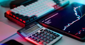 5 Money Management Tips For Young Professionals Calculator, chart, and keyboard on a desk representing 5 money management tips for young professionals, including budgeting, debt management, and financial planning.