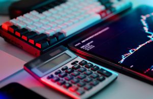 5 Money Management Tips For Young Professionals Calculator, chart, and keyboard on a desk representing 5 money management tips for young professionals, including budgeting, debt management, and financial planning.