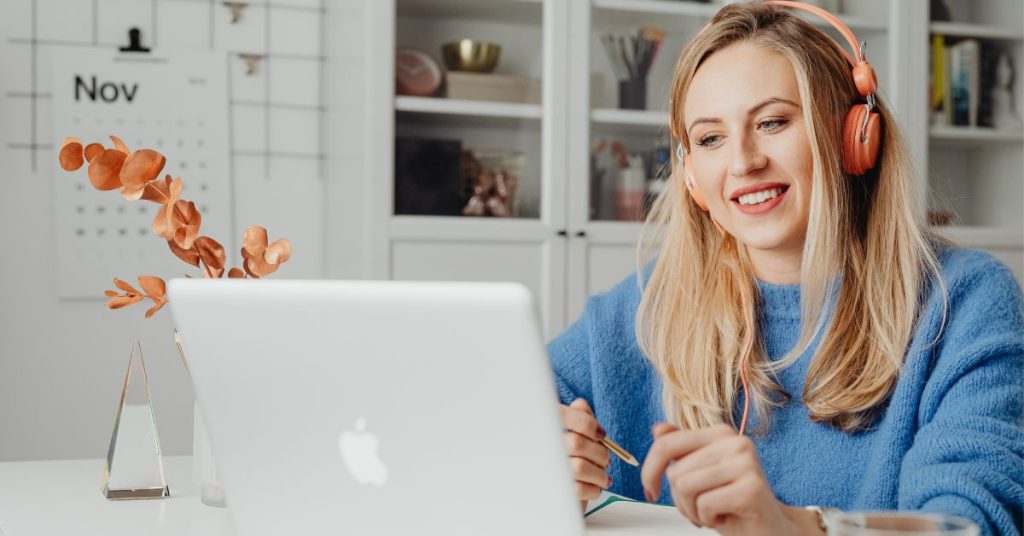A woman using Google Gemini AI for remote work productivity, smiling while working on her laptop with a pencil in hand.