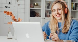 How to Use Google Gemini AI for Remote Work Productivity: Tools, Tips & Best Practices A woman using Google Gemini AI for remote work productivity, smiling while working on her laptop with a pencil in hand.