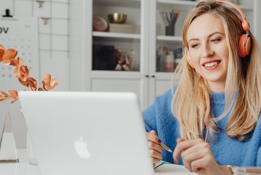 How to Use Google Gemini AI for Remote Work Productivity: Tools, Tips & Best Practices A woman using Google Gemini AI for remote work productivity, smiling while working on her laptop with a pencil in hand.
