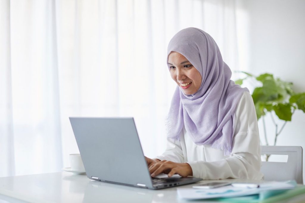 Smiling woman working on laptop using free AI tools for productivity at home office.