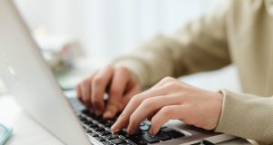 Top 15 Websites to Find Freelance Work in 2025 (Worldwide + Beginner Friendly) Hands typing on a laptop in a bright workspace while researching the top 15 websites to find freelance work in 2025