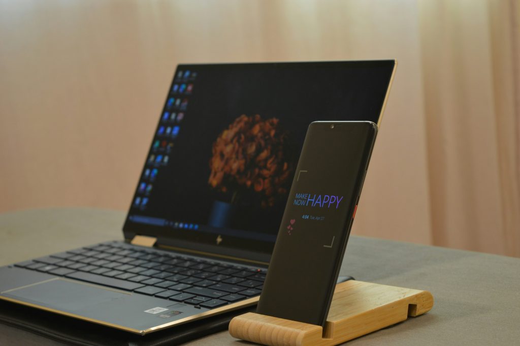 Laptop and phone on wooden stand on grey table – how to know fake vs original tech gadgets before you buy online
