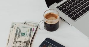 How to Open a Dollar Domiciliary Account in Nigeria Laptop, coffee, and dollar notes on white table – how to open a dollar domiciliary account in Nigeria.