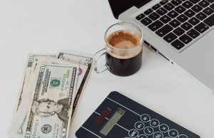 How to Open a Dollar Domiciliary Account in Nigeria Laptop, coffee, and dollar notes on white table – how to open a dollar domiciliary account in Nigeria.