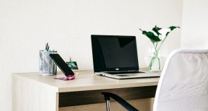 How to Build a Stylish Home Office Setup on a Budget (2025 Guide) A stylish home office setup on a budget featuring a wooden desk, laptop, phone on a stand, pen holder, and vase, creating an affordable and productive workspace.