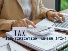 How to Register for a Tax Identification Number (TIN) in Nigeria: Complete 2026 Step-by-Step Guide Close-up of hands reviewing tax documents with a calculator and laptop, representing TIN registration in Nigeria 2026