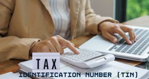 How to Register for a Tax Identification Number (TIN) in Nigeria: Complete 2026 Step-by-Step Guide Close-up of hands reviewing tax documents with a calculator and laptop, representing TIN registration in Nigeria 2026