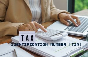 How to Register for a Tax Identification Number (TIN) in Nigeria: Complete 2026 Step-by-Step Guide Close-up of hands reviewing tax documents with a calculator and laptop, representing TIN registration in Nigeria 2026