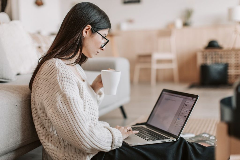 Young woman working remotely with a laptop and coffee, exploring high-income remote jobs without a degree in 2026