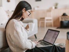 10 High-Income Remote Jobs You Can Do Without a Degree (2026 Edition) Young woman working remotely with a laptop and coffee, exploring high-income remote jobs without a degree in 2026