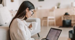 10 High-Income Remote Jobs You Can Do Without a Degree (2026 Edition) Young woman working remotely with a laptop and coffee, exploring high-income remote jobs without a degree in 2026