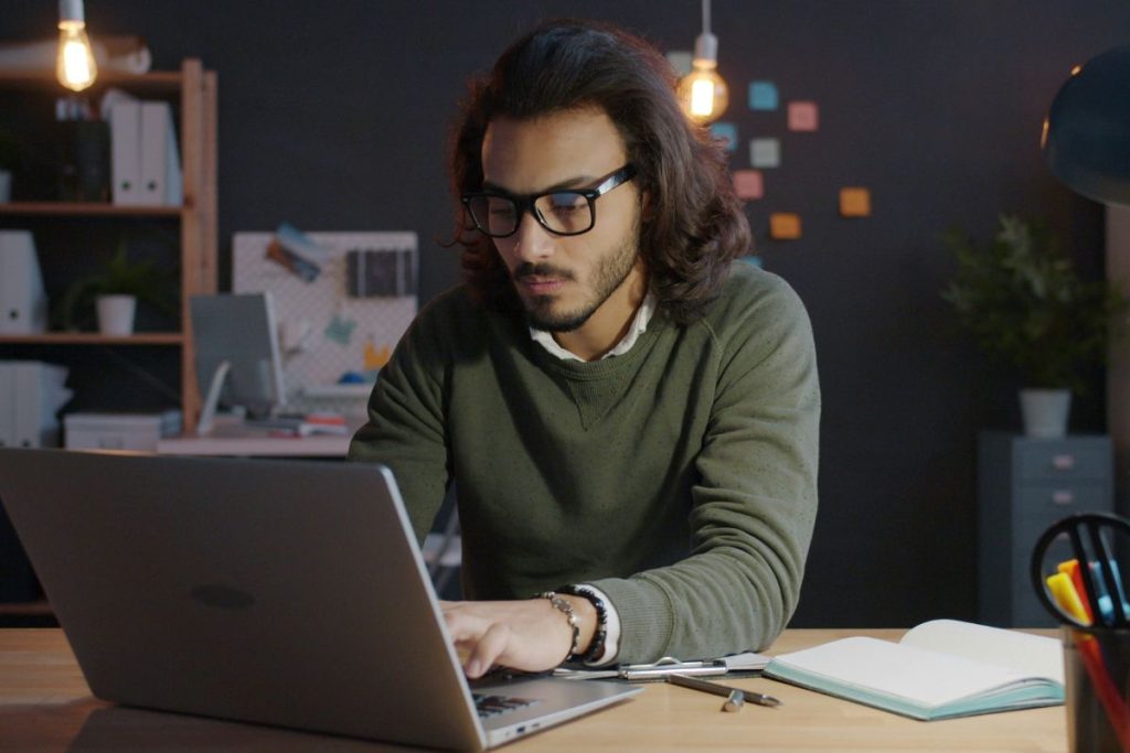 Man working on a laptop at home as he learns how to start a side hustle while working a 9-to-5