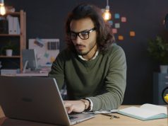 How To Start a Side Hustle While Working a 9-to-5 Man working on a laptop at home as he learns how to start a side hustle while working a 9-to-5